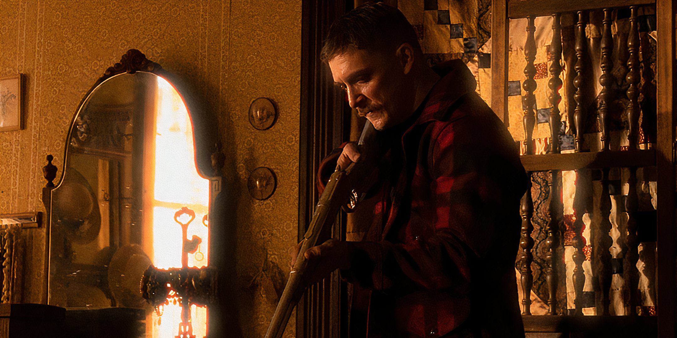 Kyle Gallner as The Demon aiming his rifle towards the ground in a bedroom in Strange Darling