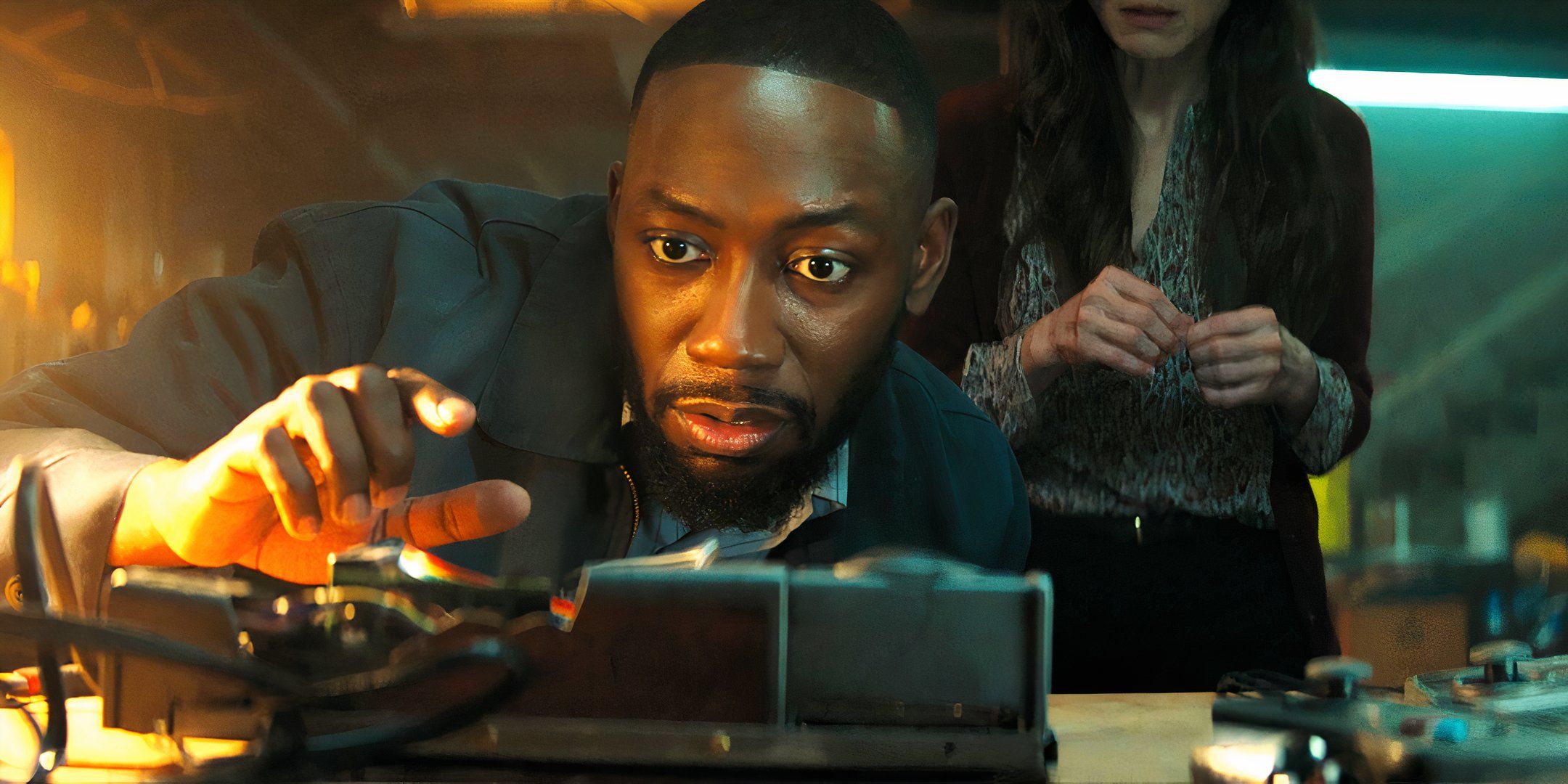 Lamorne Morris as the heater repair man looking curiously at the broken game console in Jumanji The Next Level