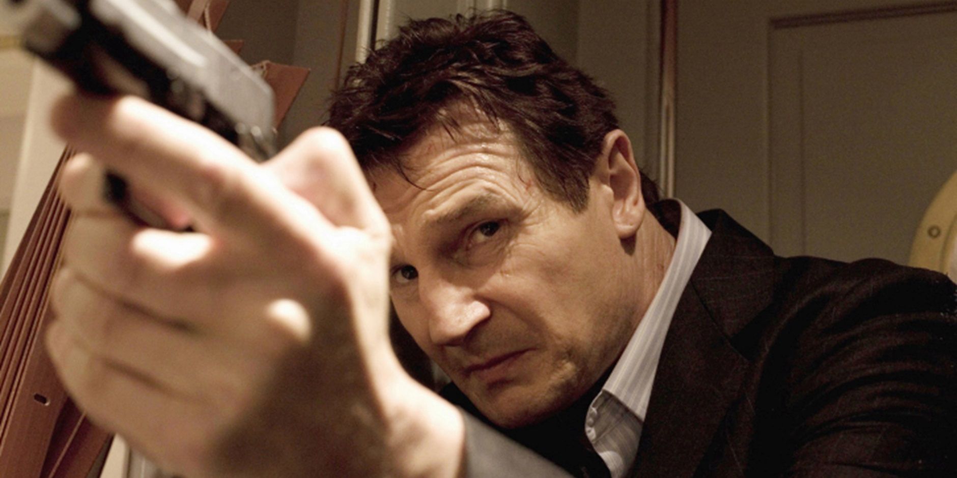 Liam Neeson segurando uma arma em Taken