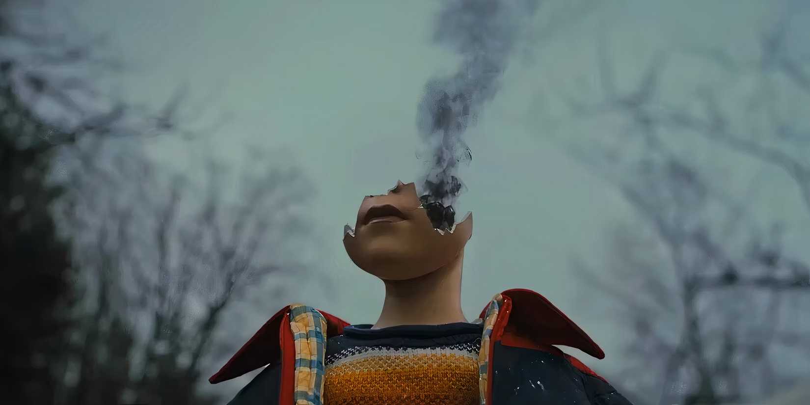 The remains of a destroyed doll with its head broken and black smoke rising from it in the film Longlegs