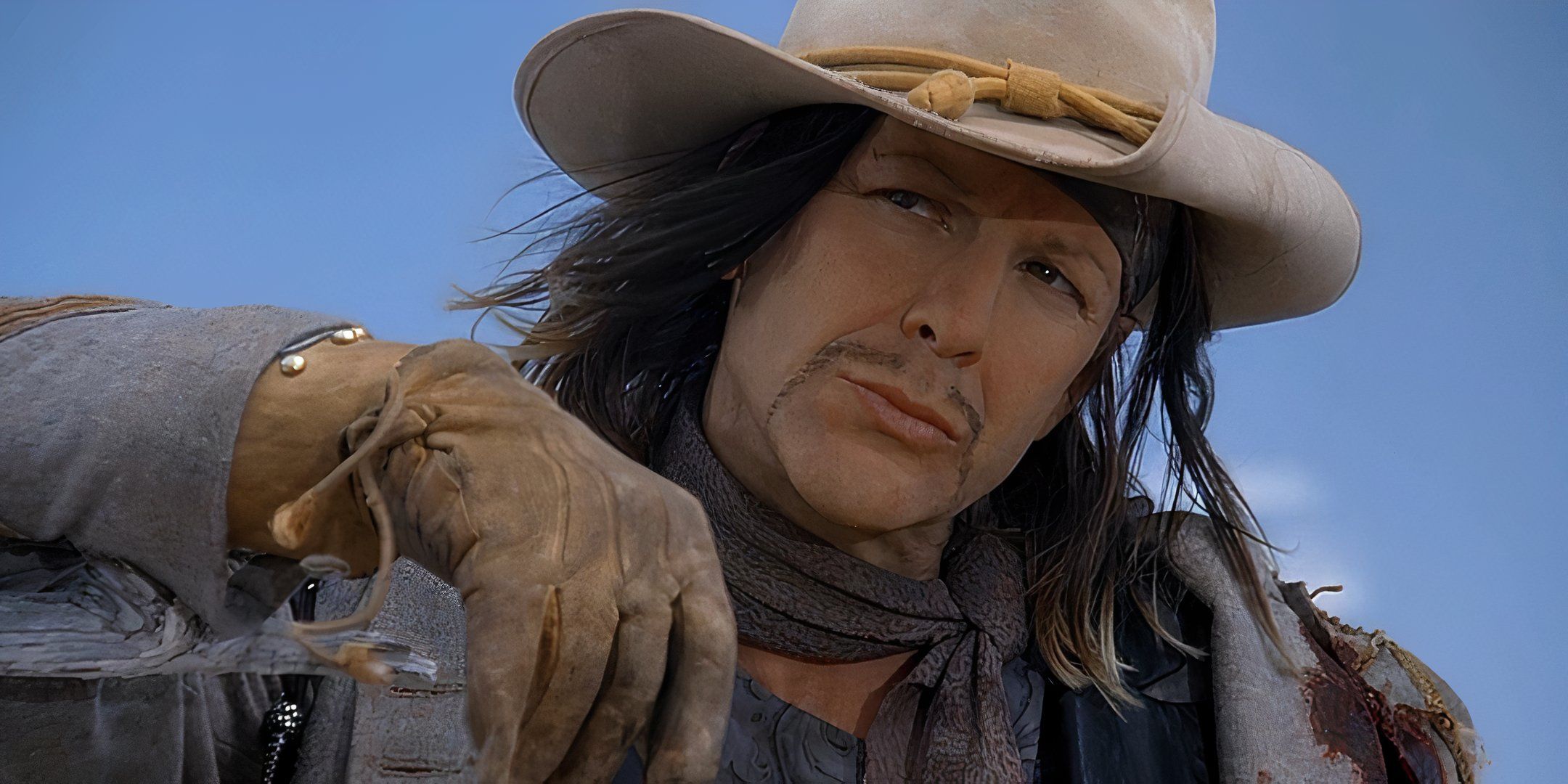 Mickey Rourke está usando um chapéu de cowboy e olhando de longe. 