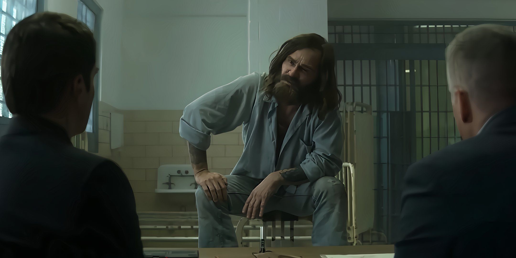 Damon Herriman as Charles Manson sits on top of a chair in Mindhunter.