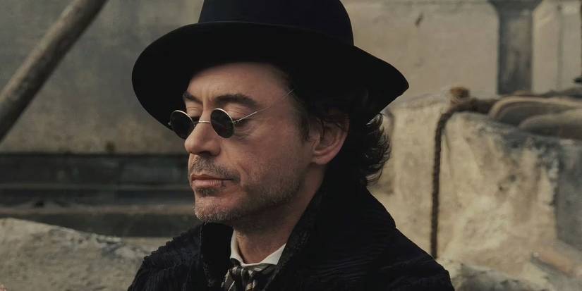 Robert Downey Junior as Sherlock Holmes wearing sunglᴀsses and a black corduroy coat.