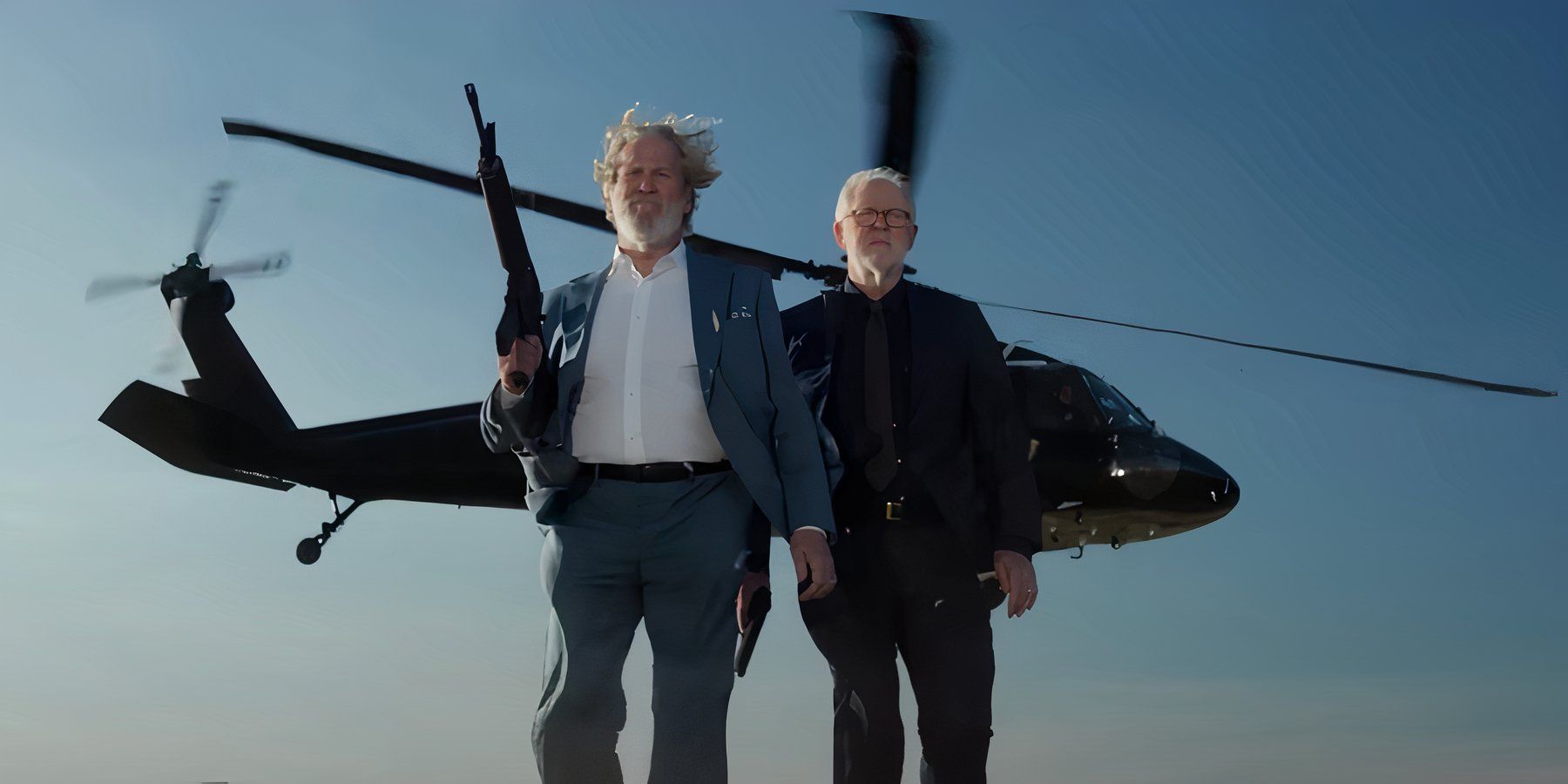 Jeff Bridges as Dan Chase next to John Lithgow as Harold Harper walking toward the camera with a helicopter in the background in The Old Man season 2