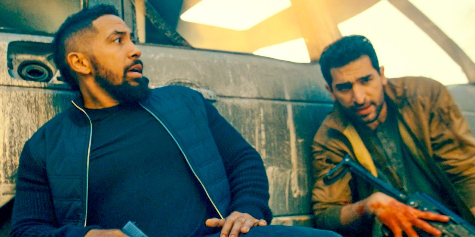 Ray (Neil Brown Jr.) and Omar Hamza (Raffi Barsoumian) using a car as a shield in a shooting against terrorists in SEAL Team Season 7 Episode 2