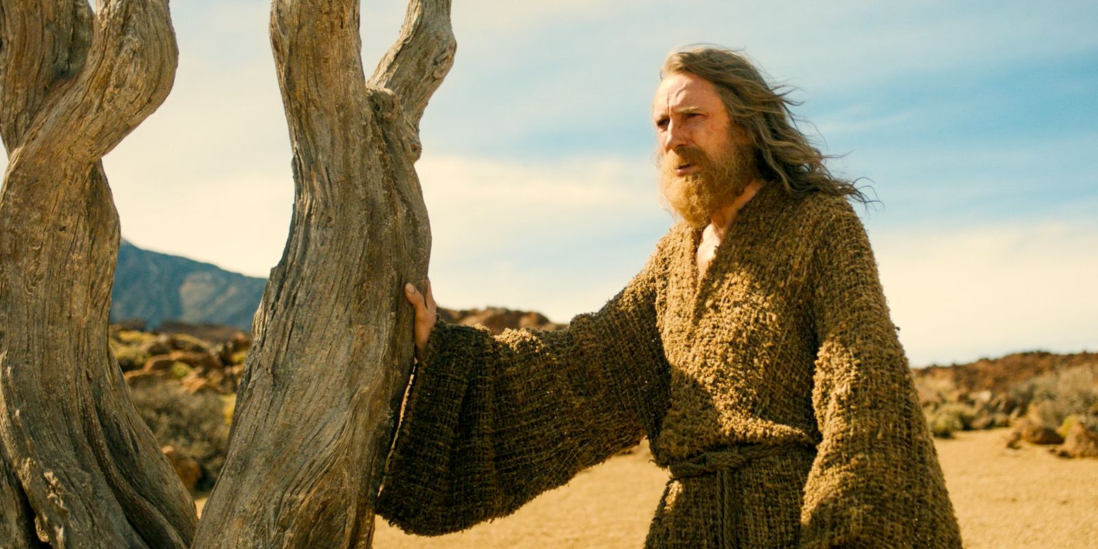 The Stranger (Daniel Weyman) tries to use his magic to obtain food from a dry tree in The Lord of the Rings: The Rings of Power Season 2 Episode 1