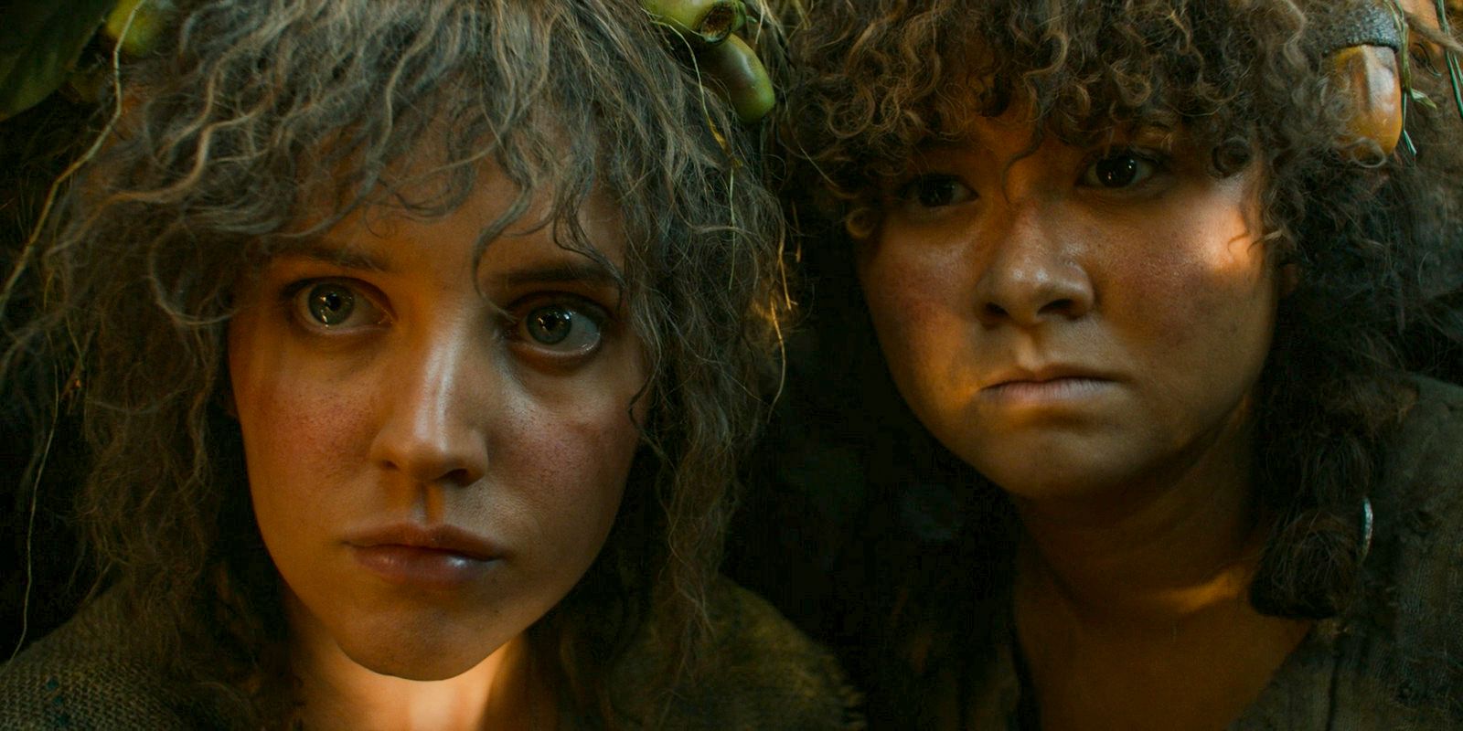 Nori (Markella Kavenagh) and Poppy (Megan Richards) hiding from Saruman's trackers in The Lord of the Rings: The Rings of Power Season 2 Episode 2