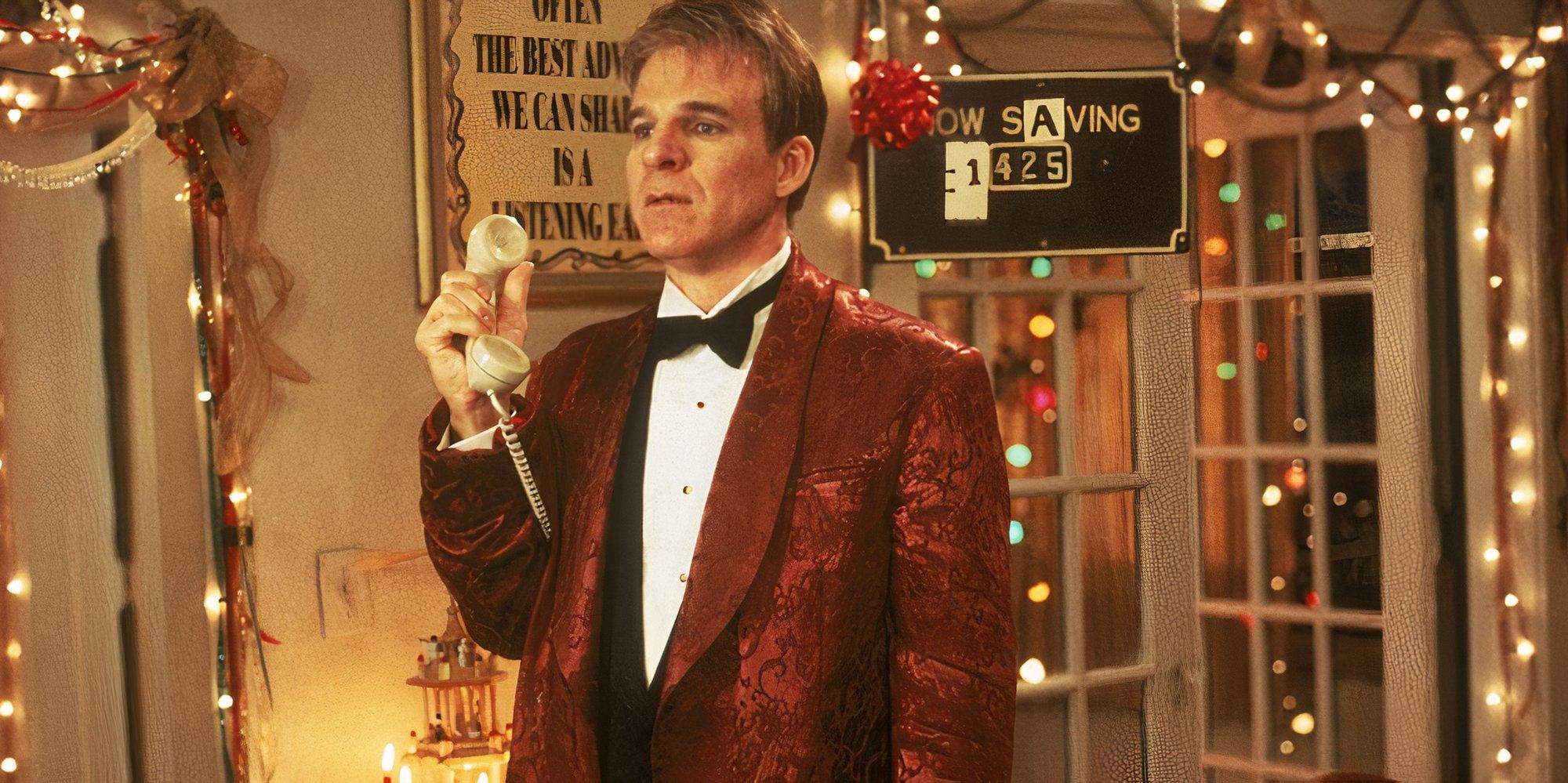 Steve Martin como Philip em um terno vermelho, segurando um telefone e parecendo derrotado, em Mixed Nuts.