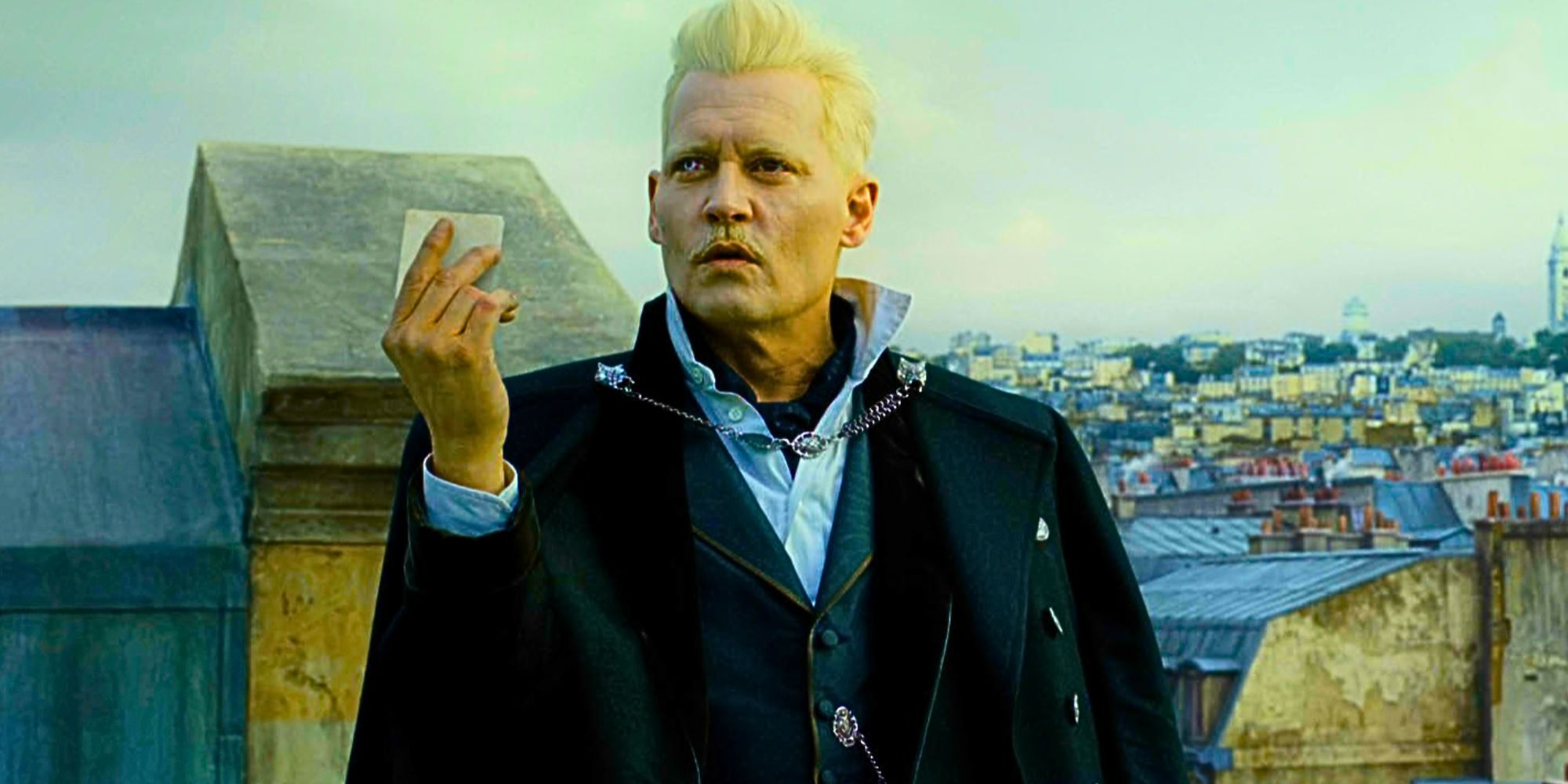 Johnny Depp segurando um pedaço de papel como Gellert Grindelwald em Animais Fantásticos: Os Crimes de Grindelwald