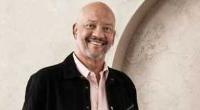 the golden bachelorette's RJ smiling broadly in business casual attire