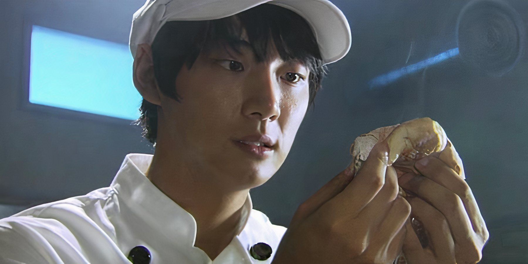 A young man in a chef coat pulls apart a piece of bread in the K-drama Bread Love And Dreams