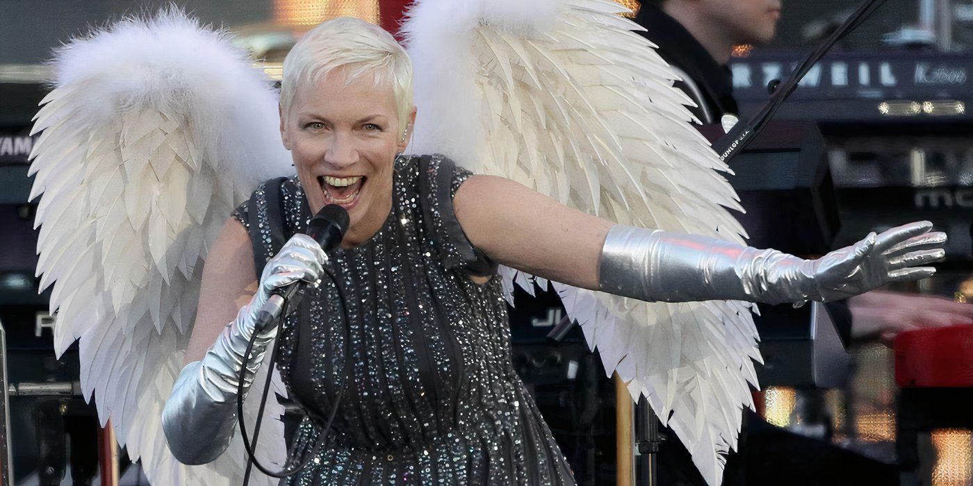 Annie Lennox se apresentando no palco com asas de anjo e sorrindo