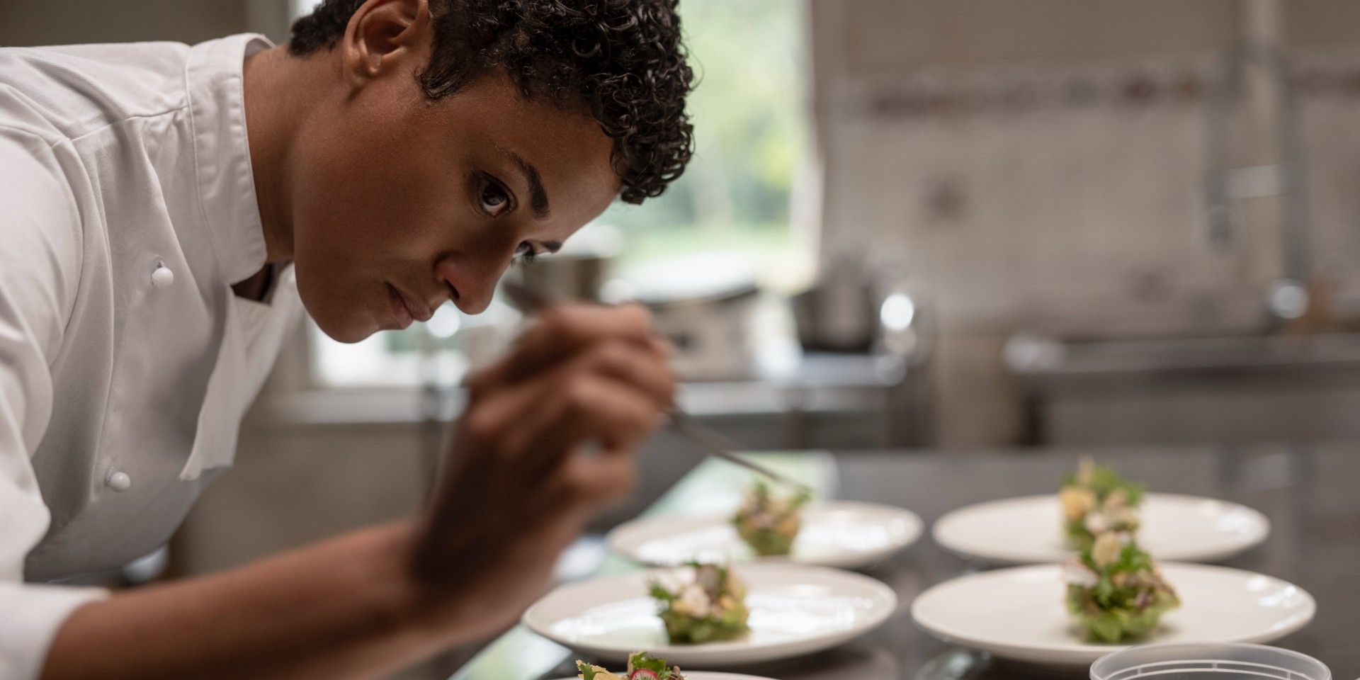 Ariana Debose se inclina sobre um prato enquanto arruma a comida nele em House of Spoils