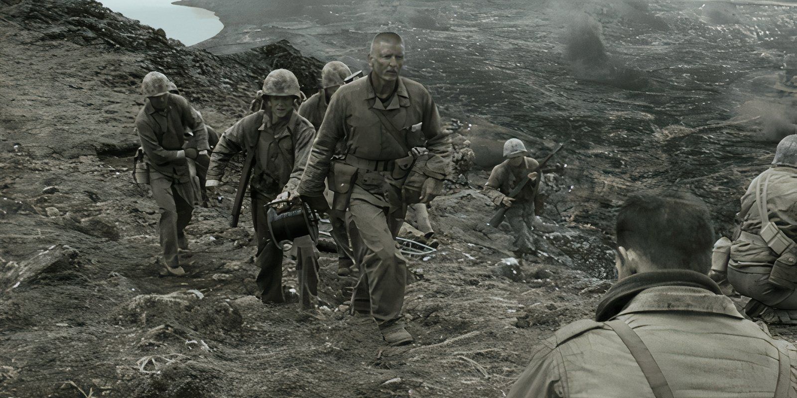 Barry Pepper walking through a battlefield with American Marines in Flags of Our Fathers