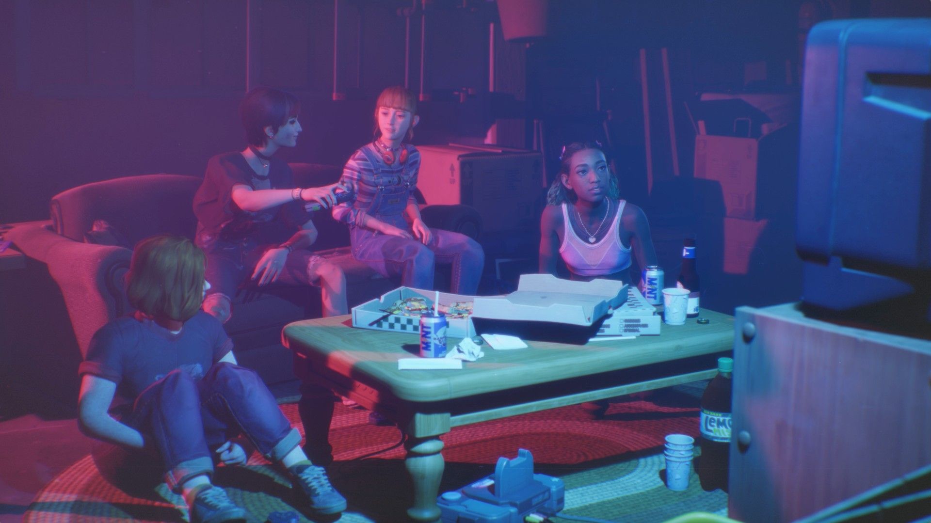 Bloom &amp; Rage group of four teenage girls grouped around a TV watching it, a pizza box is on the table in the middle.