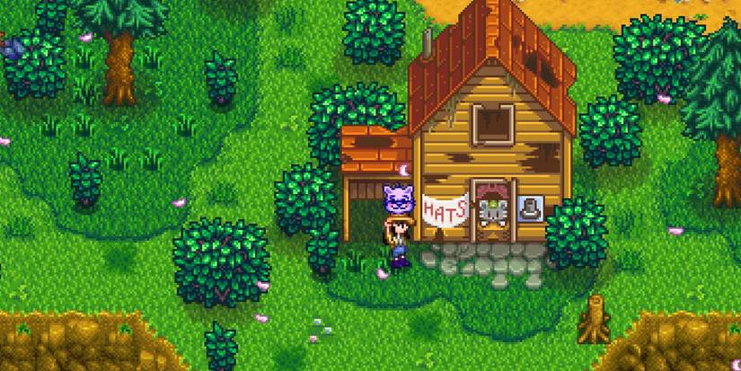 Farmer holding the ConvernedApe hat outside of Hat Mouse's shop.