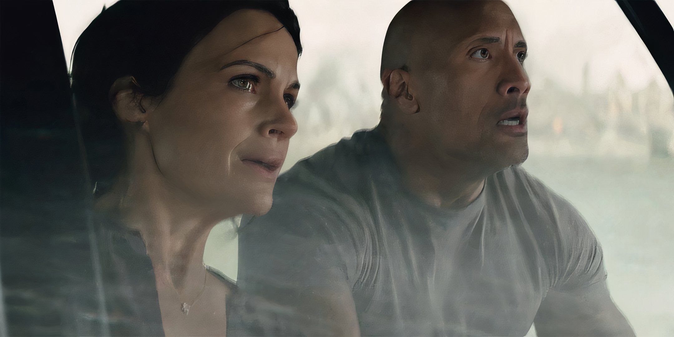 Dwayne Johnson as Ray and Carla Gugino as Emma looking worried while driving a boat in San Andreas