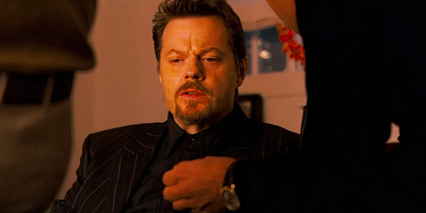 Eddie Izzard como Roman sentado en una oficina en Ocean's Thirteen