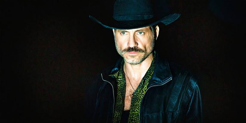 Edgar Ramirez against a black background wearing a cowboy hat in Emilia Perez