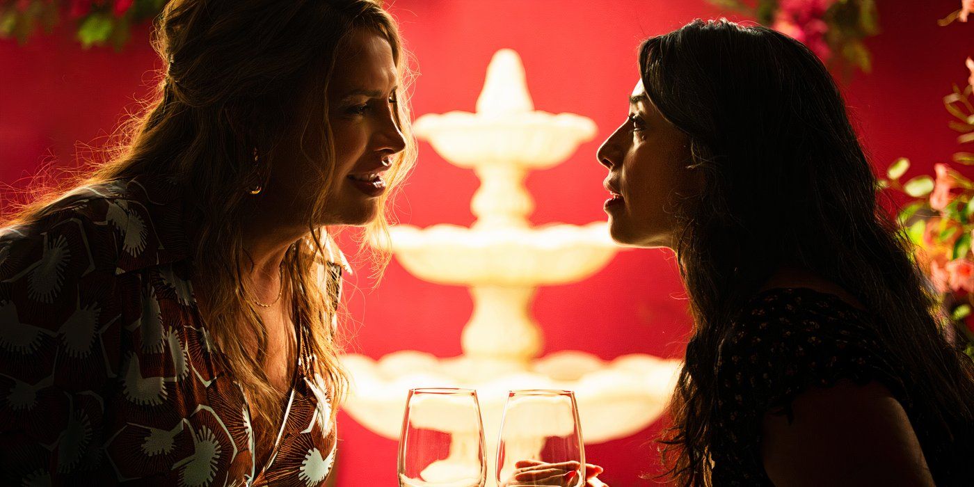 Emilia and Epifamía stare at each other across the table while on a date with a fountain in the background in Emilia Perez