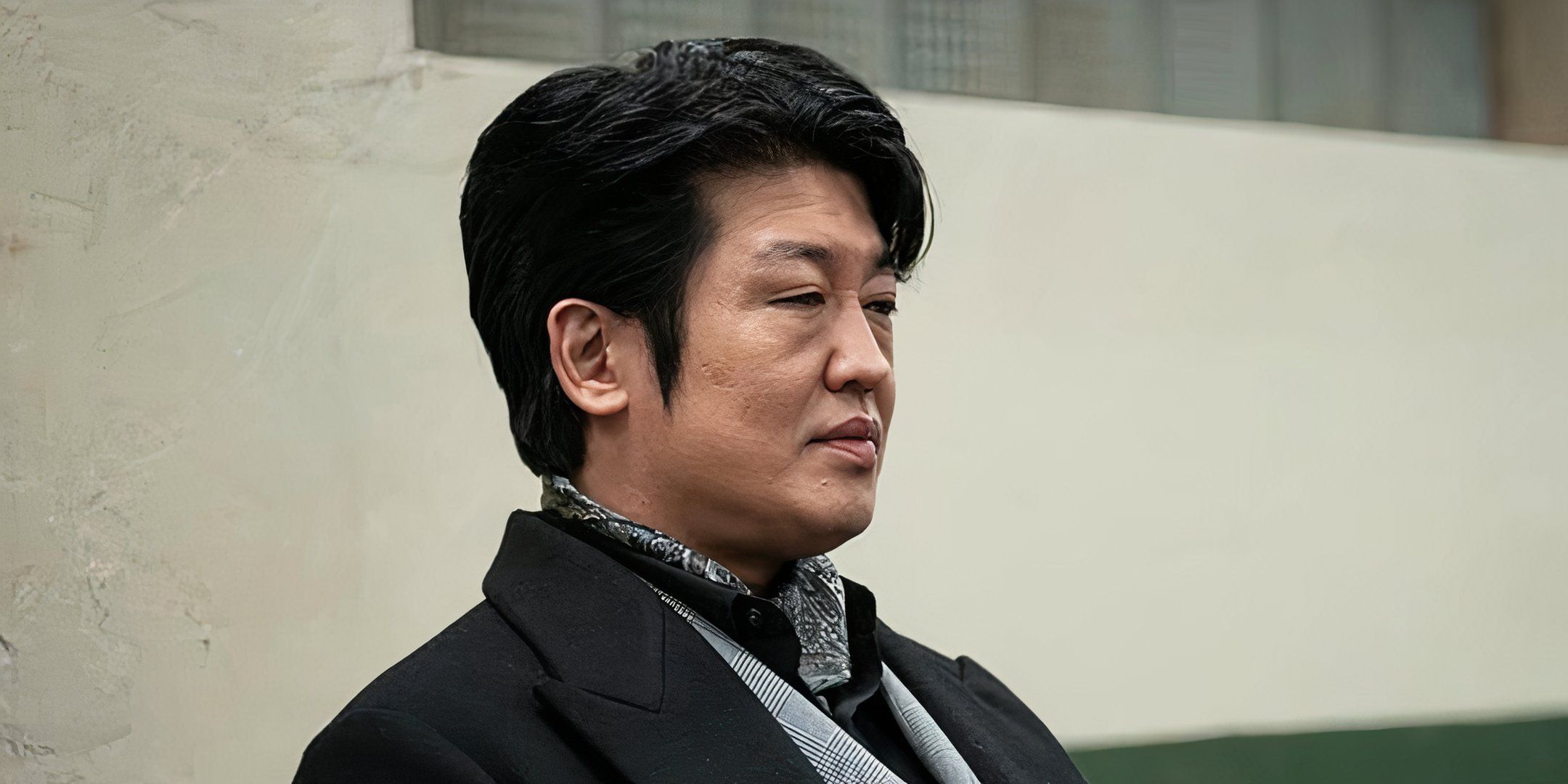 Heo Sung-tae sits in a chair and has a serious look on his face. 