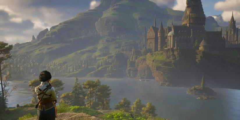 A lone witch looks out over The Black Lake in Hogwarts Legacy.