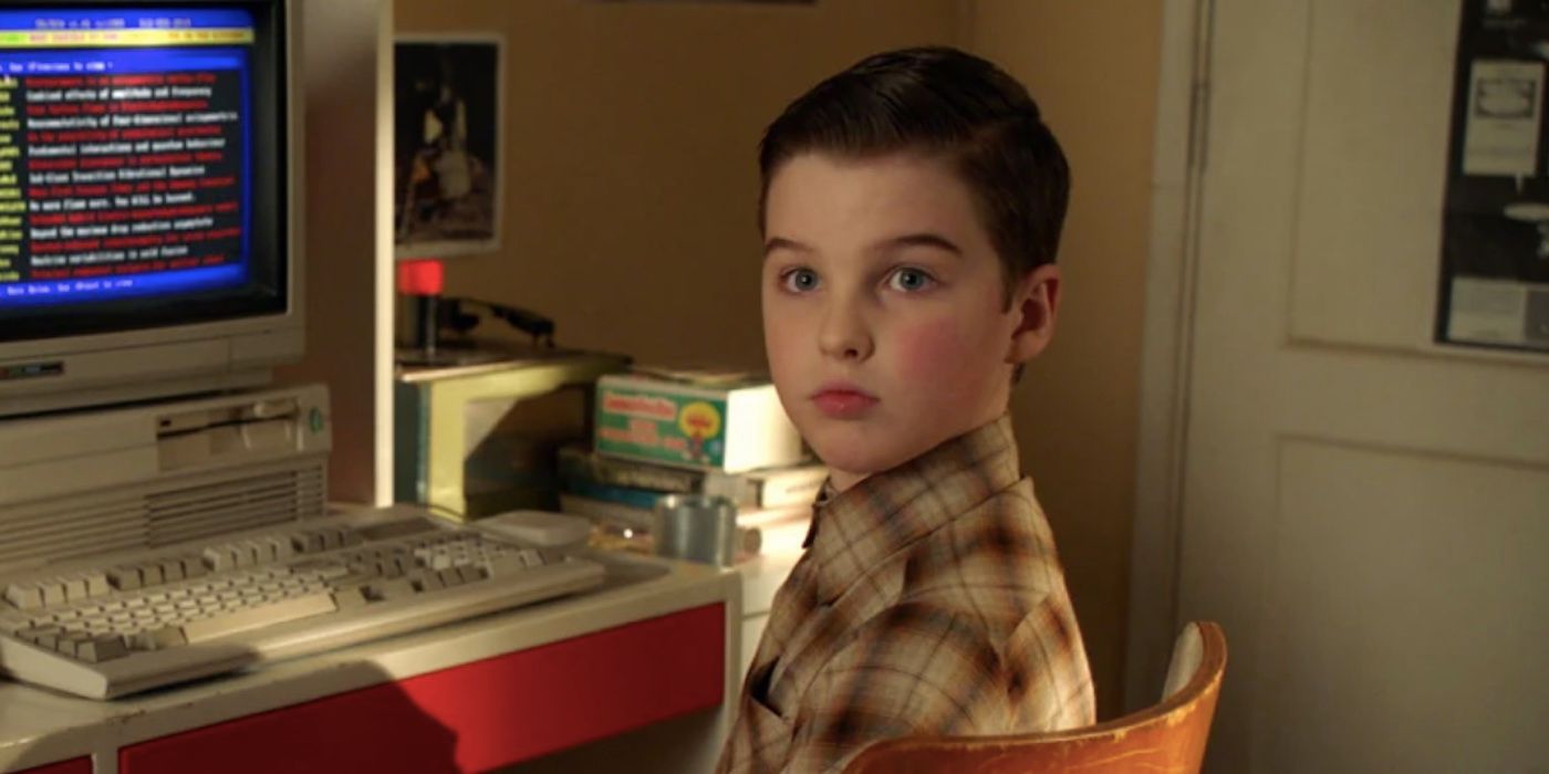 Iain Armitage's Sheldon sits at a computer and talks to someone offscreen in Young Sheldon season 3 episode 7