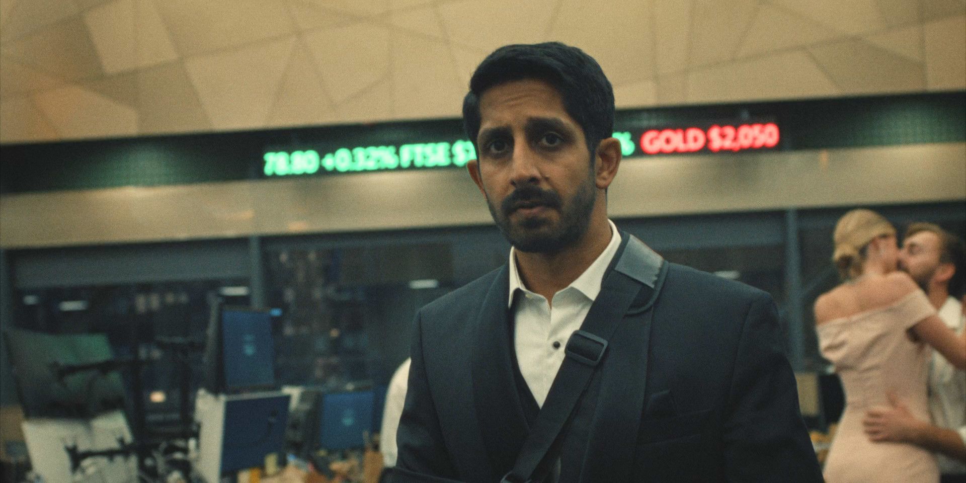 Rishi (Sagar Radia) walks through the bustling Pierpoint office, a look of concern on his face in Industry season 3, episode 7.