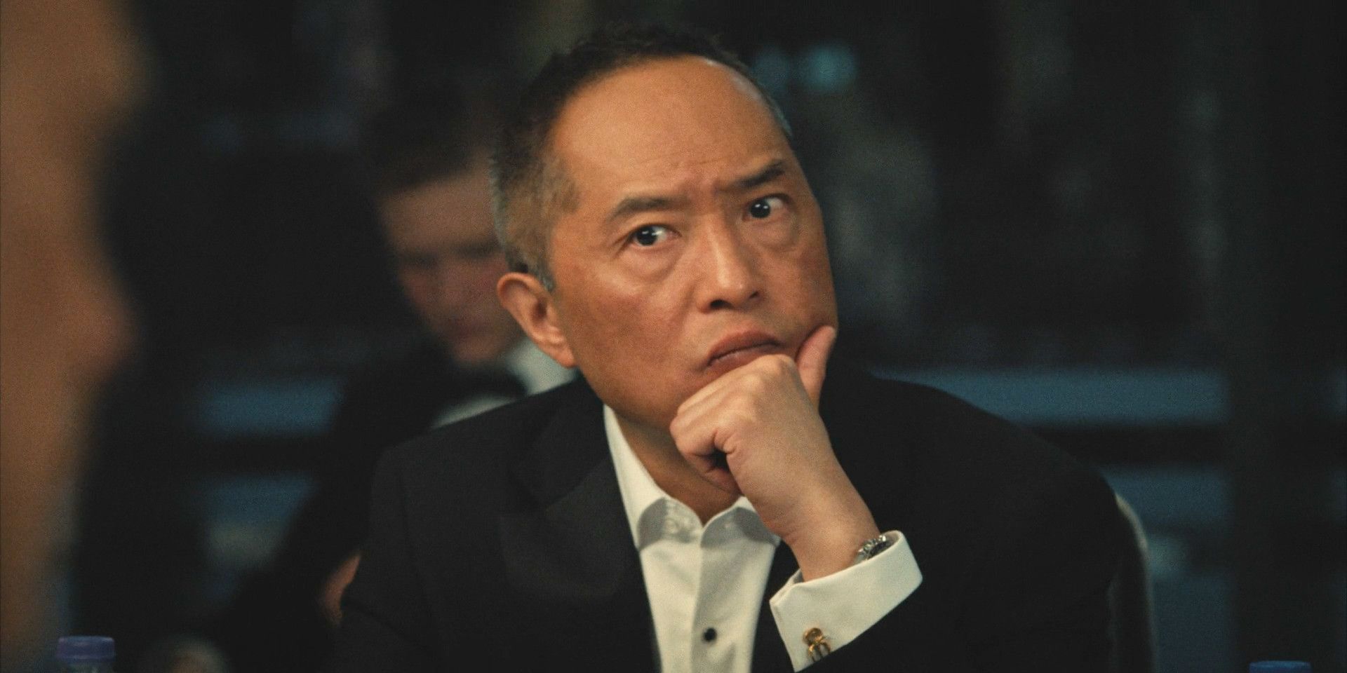 Eric Tao (Ken Leung) sits at the table, his hand resting thoughtfully on his chin in Industry season 3 episode 7
