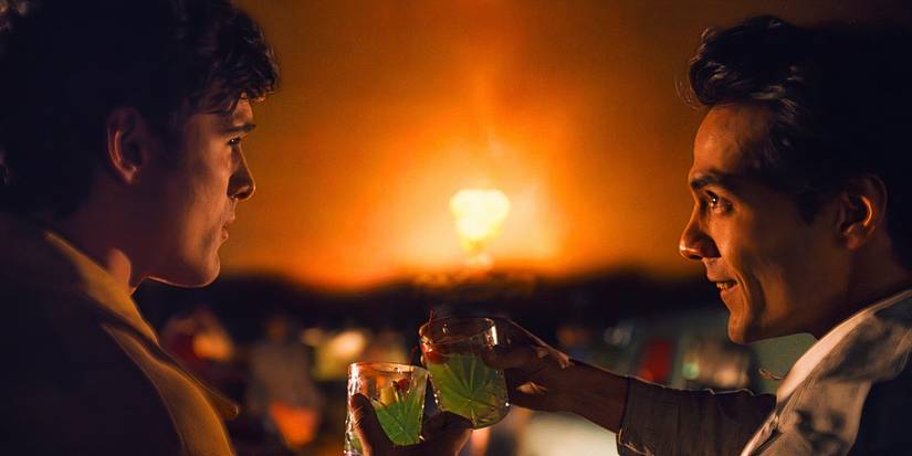 Jacob Elordi and Diego Calva cheers with drinks as an explosion goes off in the background in On Swift Horses