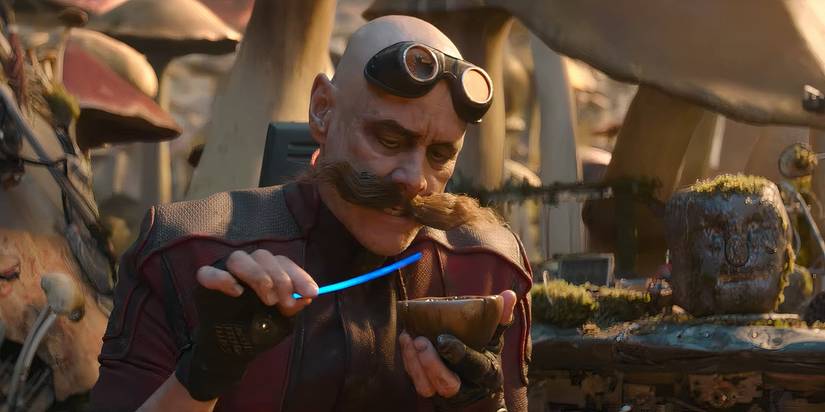 Jim Carrey as Dr. Robotnik holding a cup next to a rock with a face on it - Sonic the Hedgehog 2