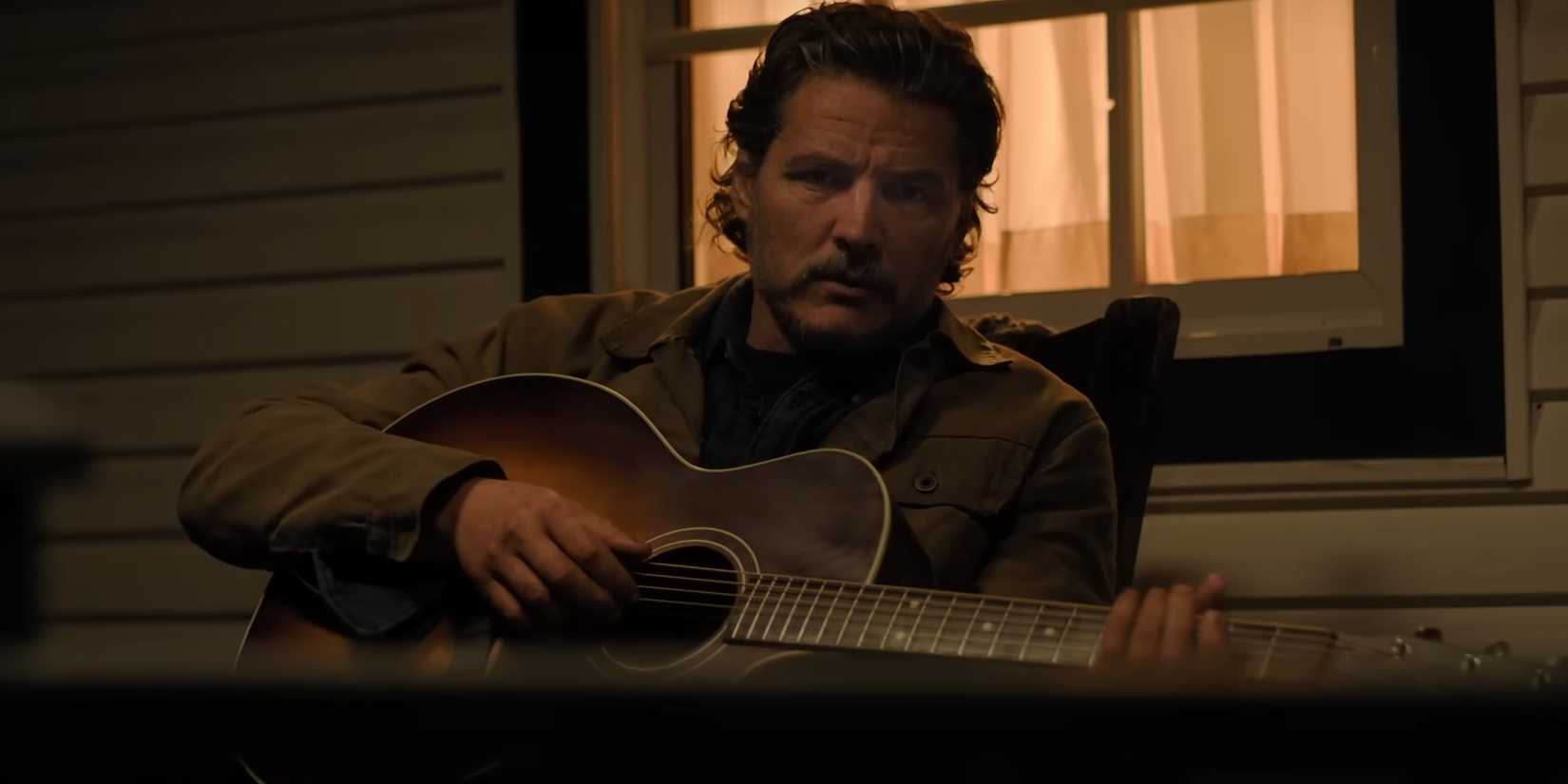 Joel (Pedro Pascal) sits on his porch playing his guitar in The Last of Us