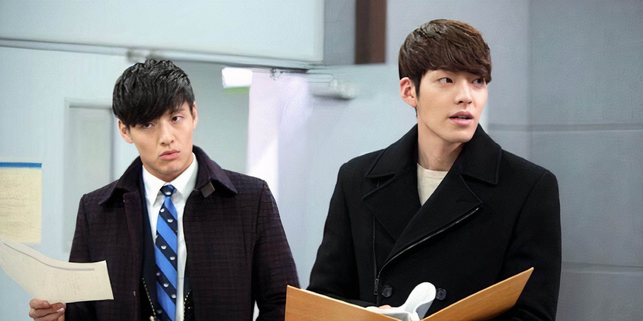 Kang Ha-neul y Kim Woo-bin están en el pasillo, sosteniendo papeles.