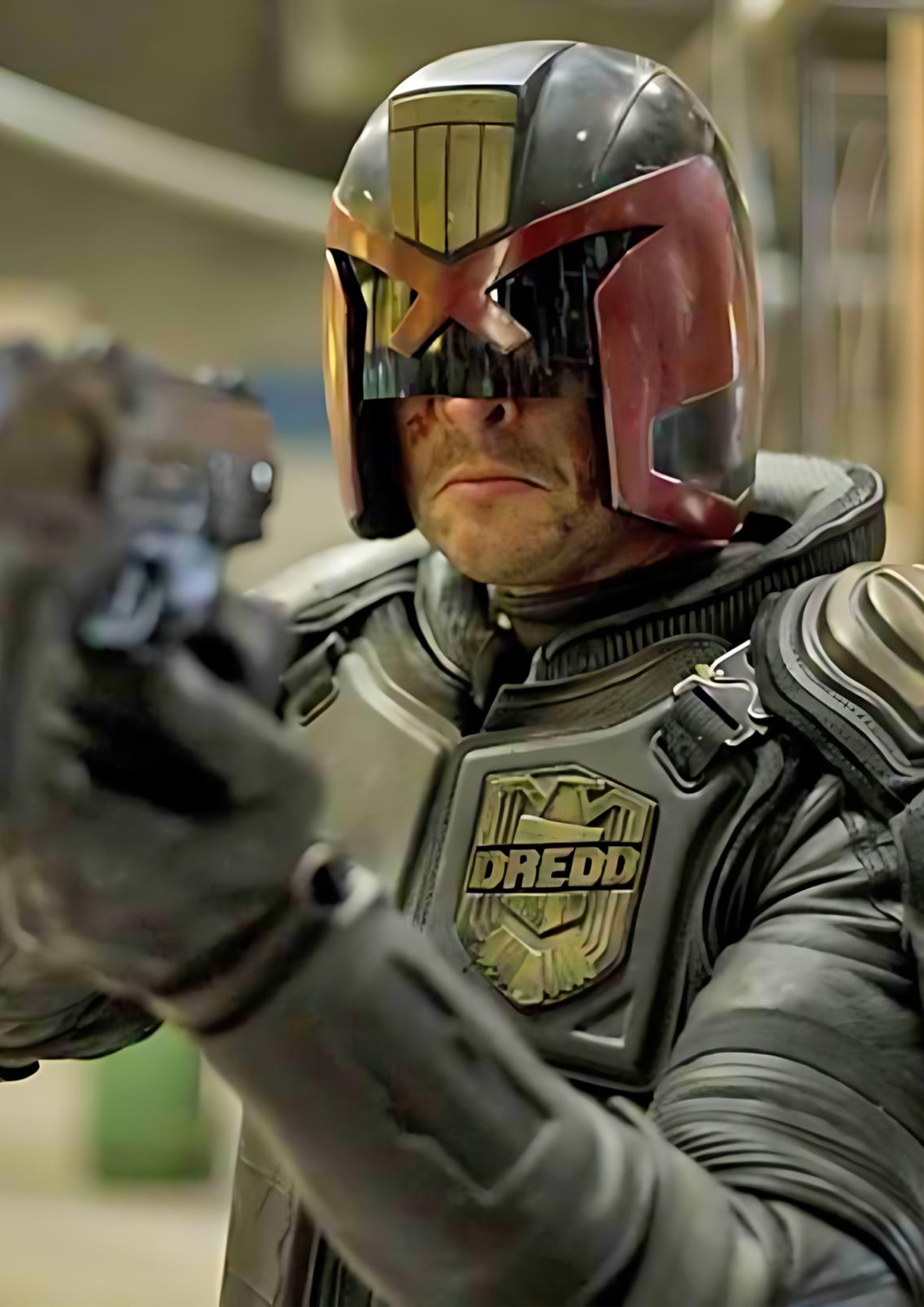 Karl Urban as Judge Dredd in Dredd (2012) holding a gun and frowning