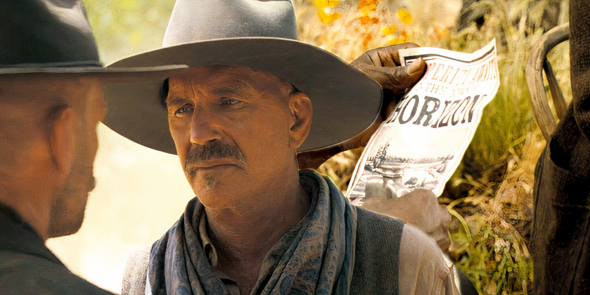 Kevin Costner gives a stern stare at someone while there is a Horizon column in the background in Horizon An American Saga