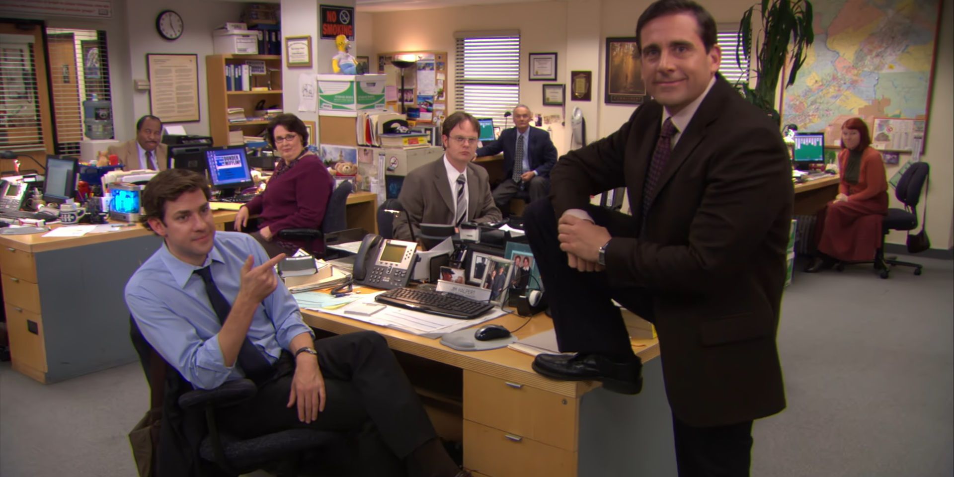 Michael leans on Jim's desk in The Office