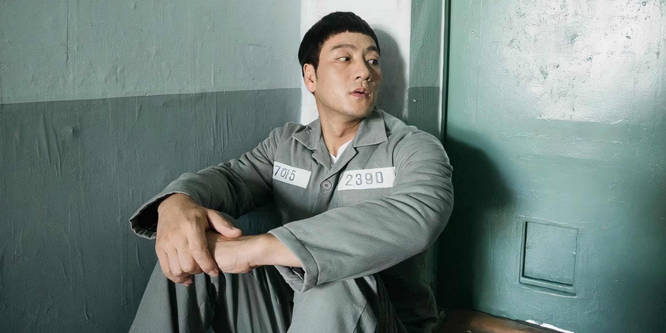 Park Hae-soo sits on the ground and leans up agains the walls of a prison cell.