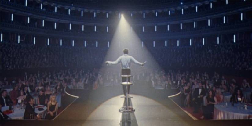 Robbie Williams in front of a seated crowd in Better Man
