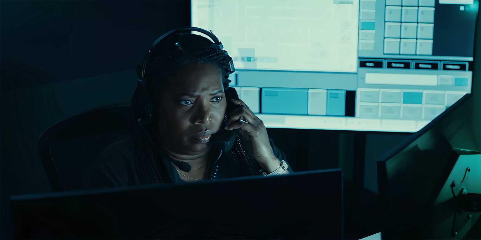 Saidah Arrika Ekulona as Cici talking on the phone and looking serious at her desk in Amber Alert