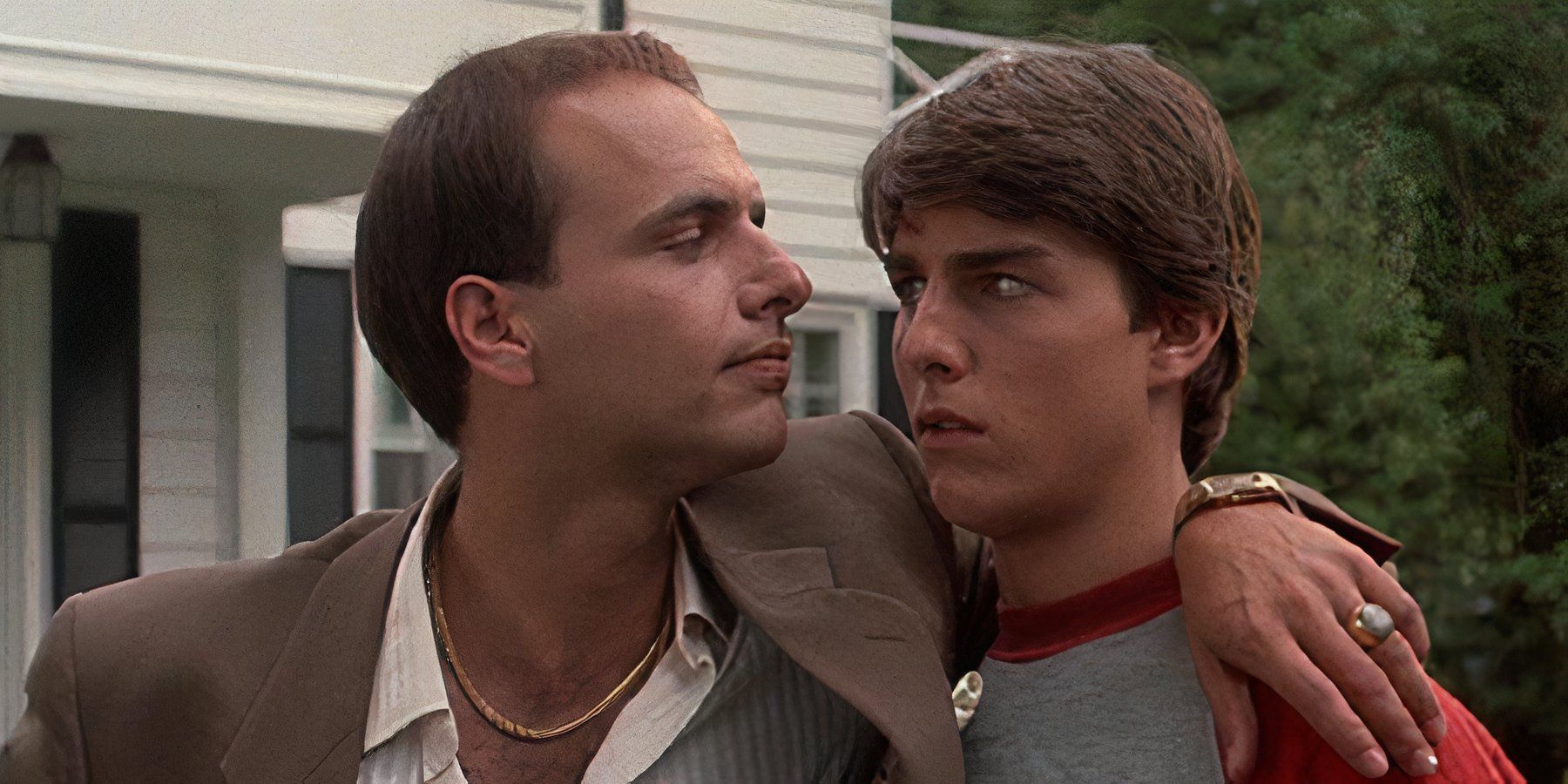 Joe Pantoliano with his arm around Tom Cruise's shoulder looking at him menacingly in Risky Business