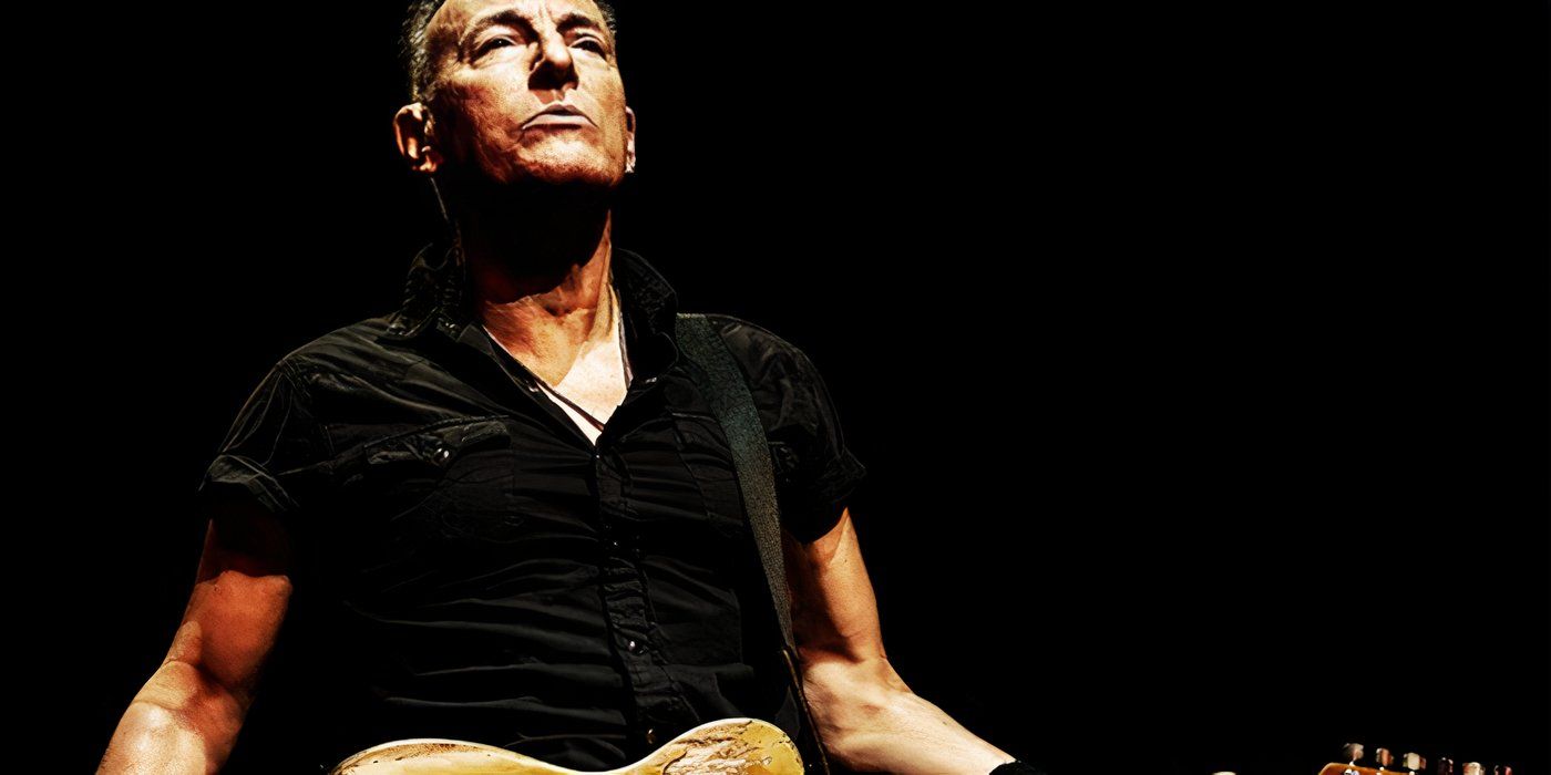 Bruce Springsteen with his guitar against a black background