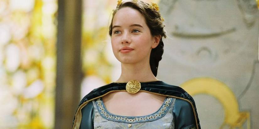 Anna Popplewell as Susan Pevensie wearing a crown and smiling while standing in a woodland in The Chronicles of Narnia.