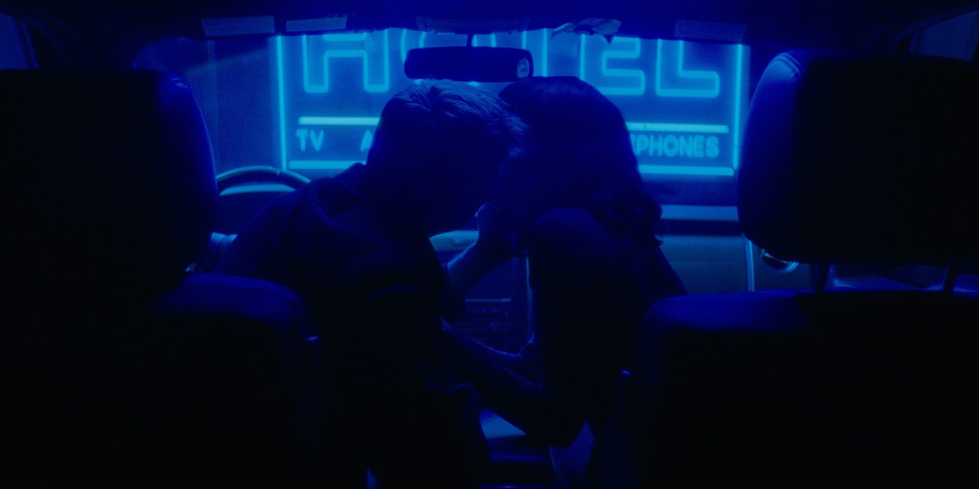 The demon and the lady kiss in blue neon light in Strange Darling