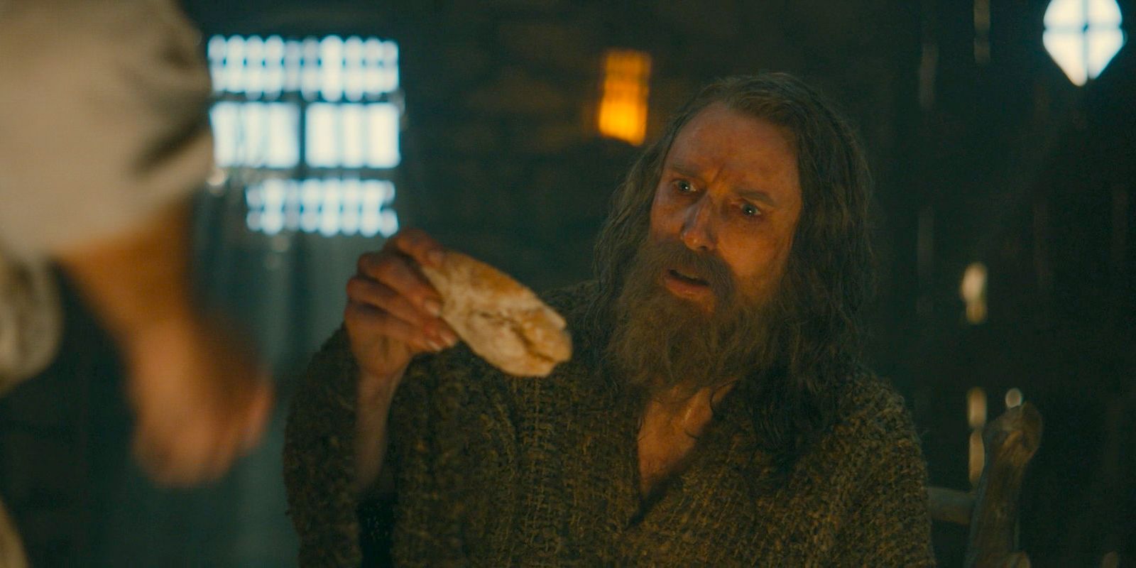 Tom Bombadil transforms a piece of the map into bread for The Stranger (Daniel Weyman) in The Lord of the Rings: The Rings of Power Season 2 Episode 4