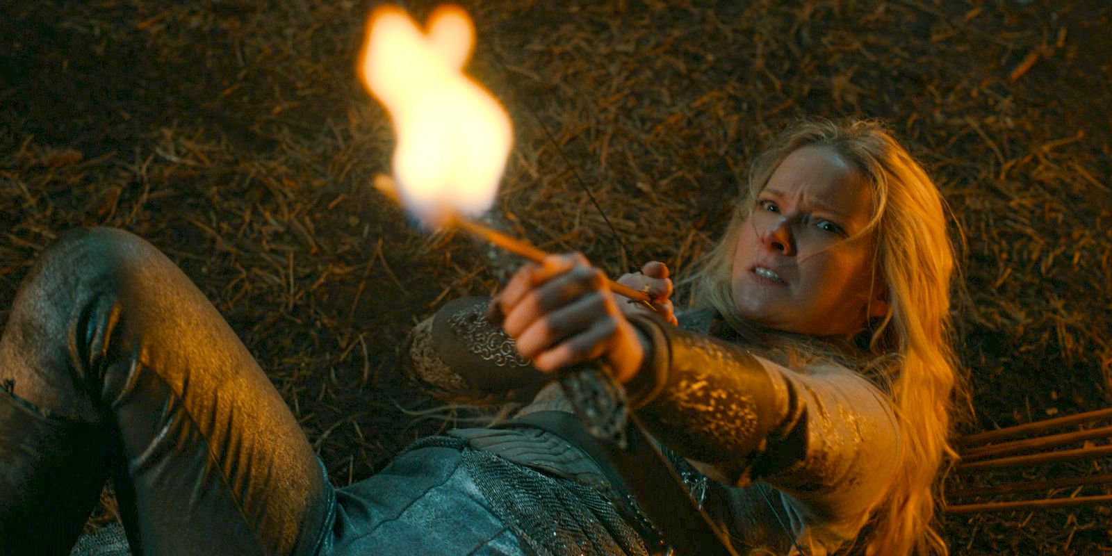 Galadriel (Morfydd Clark) on the ground, aiming a fire arrow at Adar in The Lord of the Rings: The Rings of Power Season 2 Episode 4