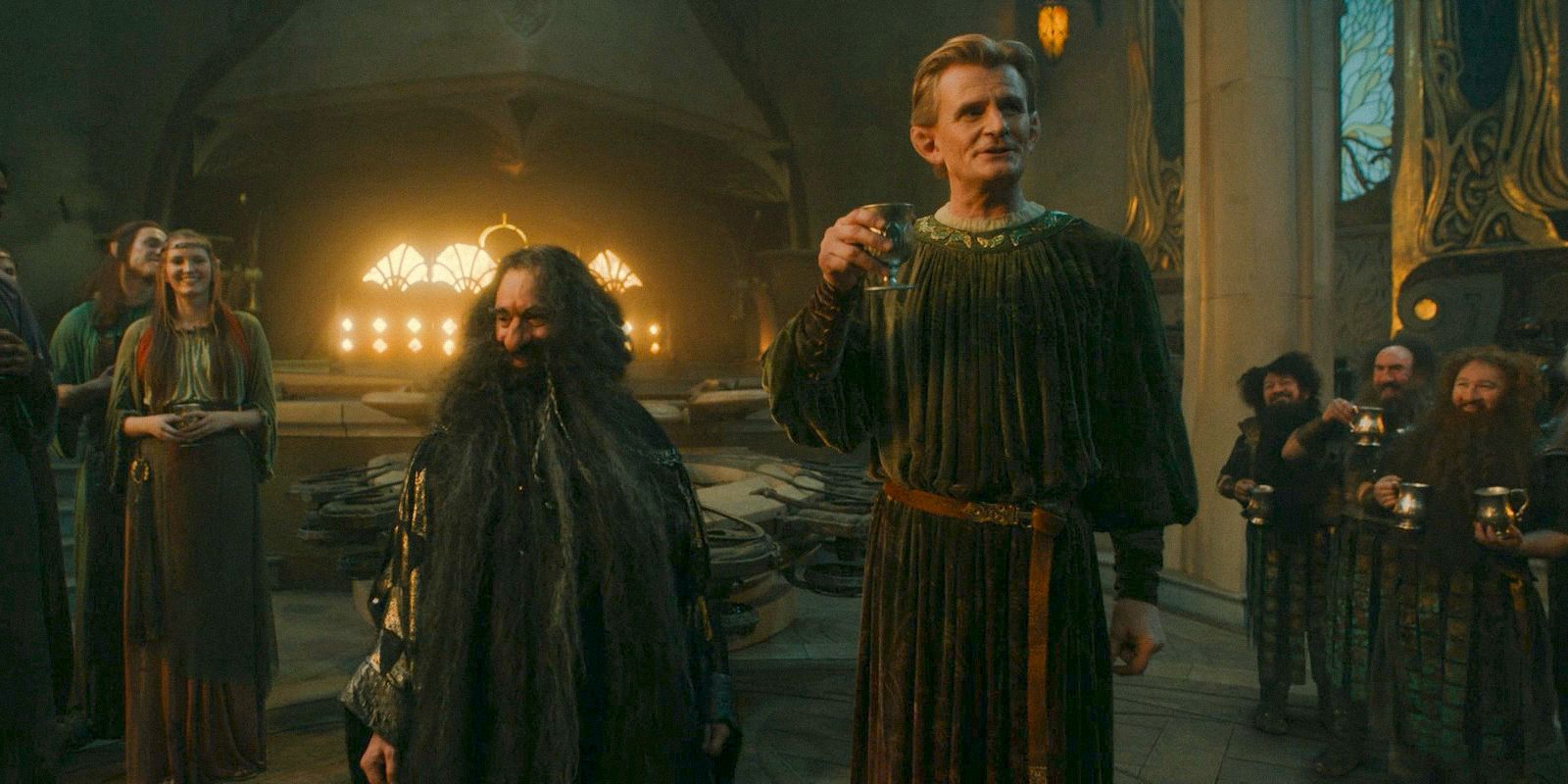 Narvi (Kevin Eldon) and Celebrimbor (Charles Edwards) toasting to the new alliance between dwarves and elves in The Lord of the Rings: The Rings of Power Season 2 Episode 5