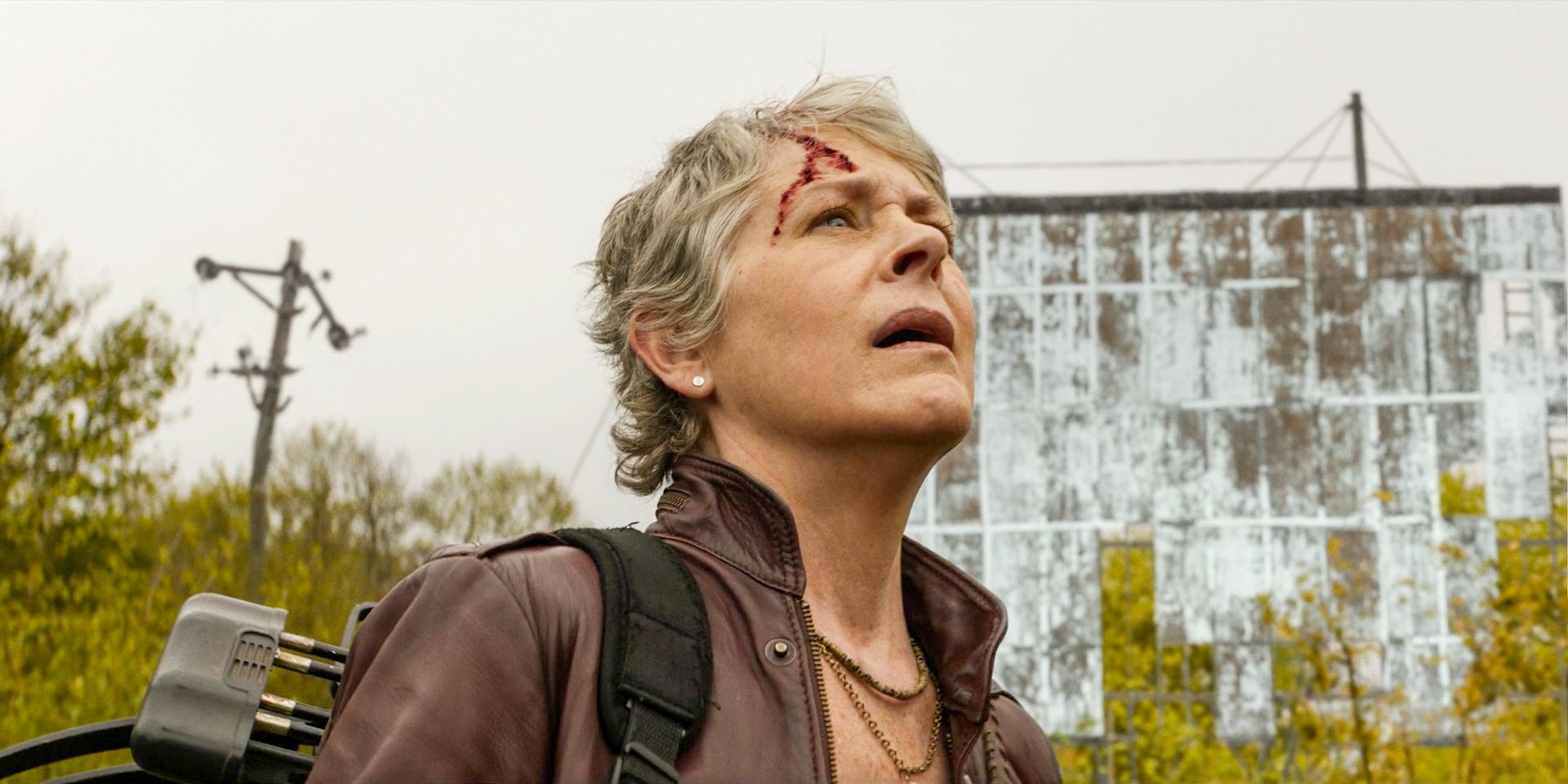 Carol Peletier (Melissa McBride) with a head wound watching a plane fly overhead in The Walking Dead: Daryl Dixon Season 2 Episode 1