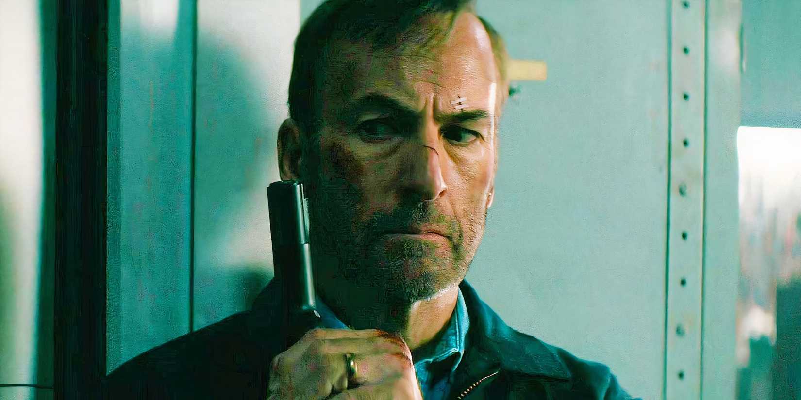 Bob Odenkirk holding a gun and looking sideways in Nobody