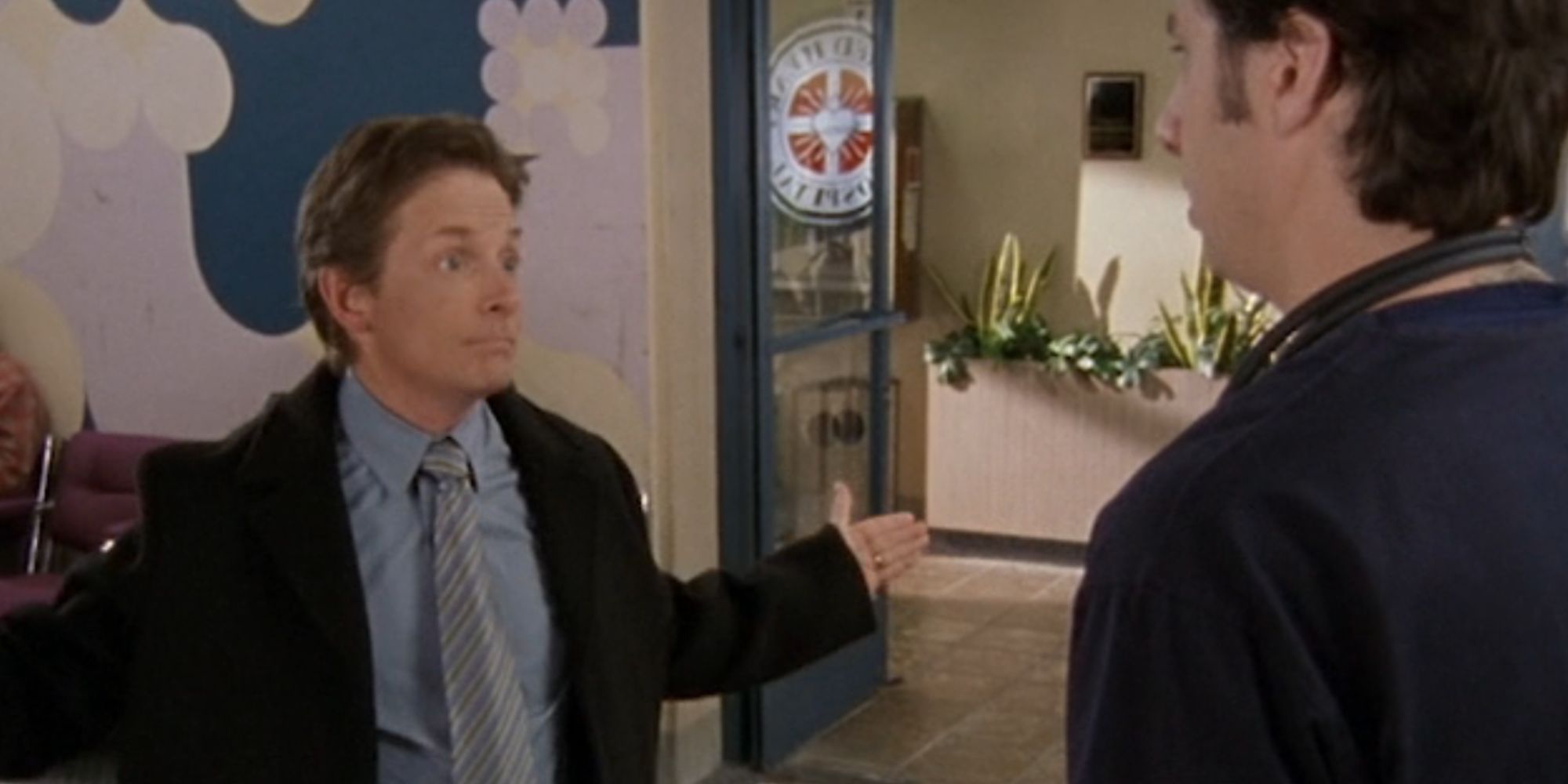 Michael J. Fox com os braços abertos como Dr. Kevin Casey em Scrubs