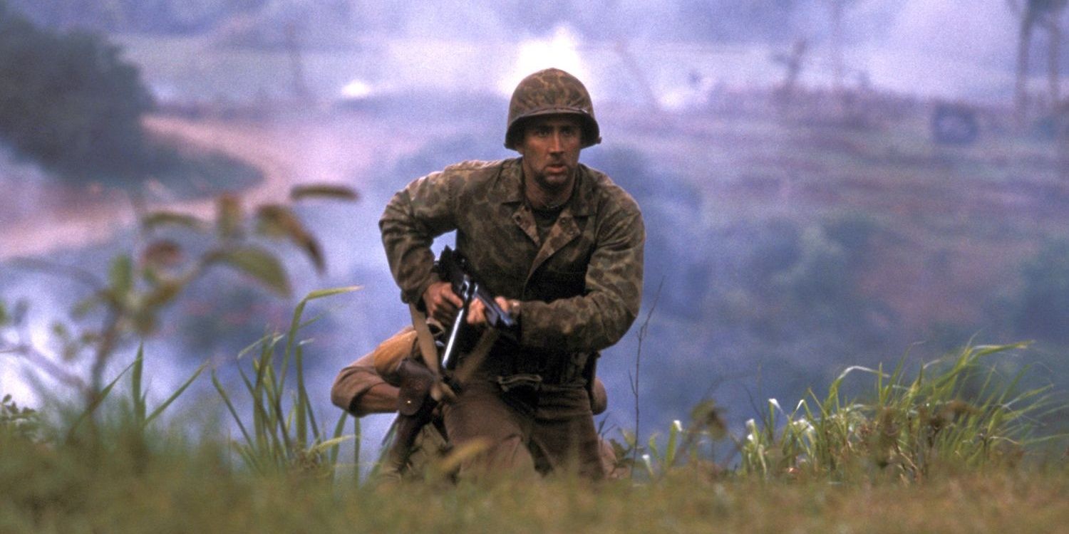 Nicolas Cage carrying a gun and moving through grass in Windtalkers